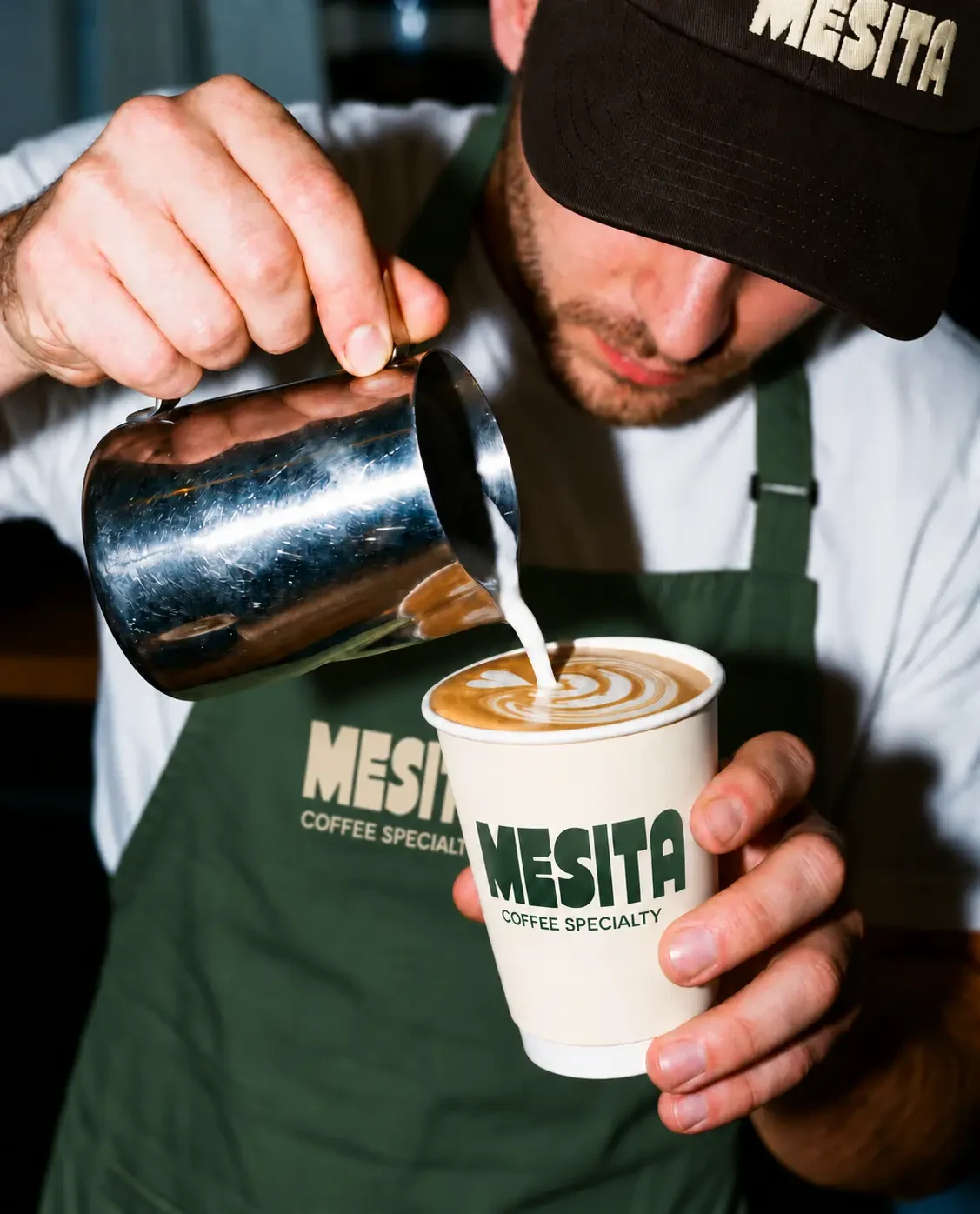 Barista con delantal y vaso de Mesita